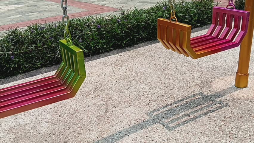 Low angle view of colorful metal swing motion in the outdoor kids playground.