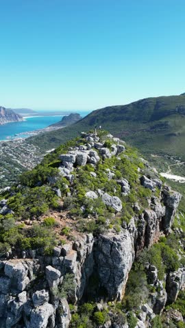 An aerial shot of a man filming the rocky coast in Hout Bay, Cape Town, South Africa