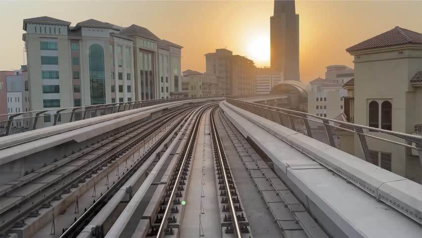 UAE, Dubai - September 5, 2024 - Dubai public transport metro train passing through platform rail with Dubai downtown or city buildings background. UAE RTA vehicle closeup exterior view.