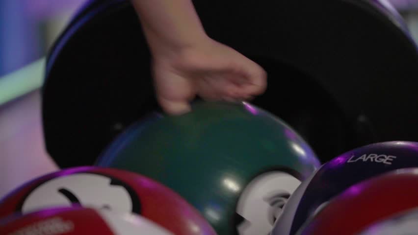 Close up of the balls coming out from bowling return machine and kid hand picking one of them