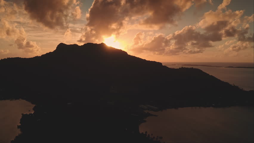 Stunning sunrise over mountain peak, warm hues sky over ocean lagoon Bora Bora island in French Polynesia. Serene idyllic exotic paradise, ideal peaceful getaway. Nature background. Aerial drone shot