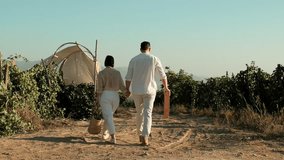 Loving couple walking through vineyards holding hands. Young woman and man dating outdoors at nature having picnic relax enjoy time together during grapes harvest season - Powered by Shutterstock - Get 15% off with code: PIKWIZARD15