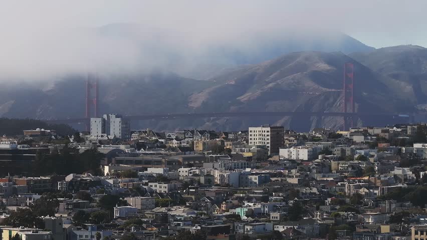 Aerial view of the Golden Gate Bridge surrounded by Fog in San Francisco, California, USA. View from the downtown of San Francisco with houses and buildings in the foreground.