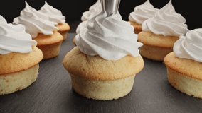 Confectioner making vanilla cupcakes for party. Decorating muffins with white cream. Home bakery concept. Decorating muffins with cream. Dolly shot using laowa probe lens. Close-up in 4K, UHD - Powered by Shutterstock - Get 15% off with code: PIKWIZARD15