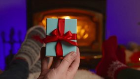 In a cozy and inviting scene, a man is seen joyfully presenting a beautifully wrapped gift in front of a warm, crackling fireplace, perfectly capturing the delightful festive spirit of Christmas - Powered by Shutterstock - Get 15% off with code: PIKWIZARD15