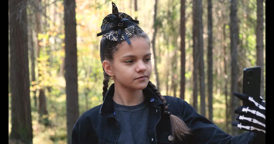 cute teenage girl in halloween costume outside in park filming stories or video calling 4k