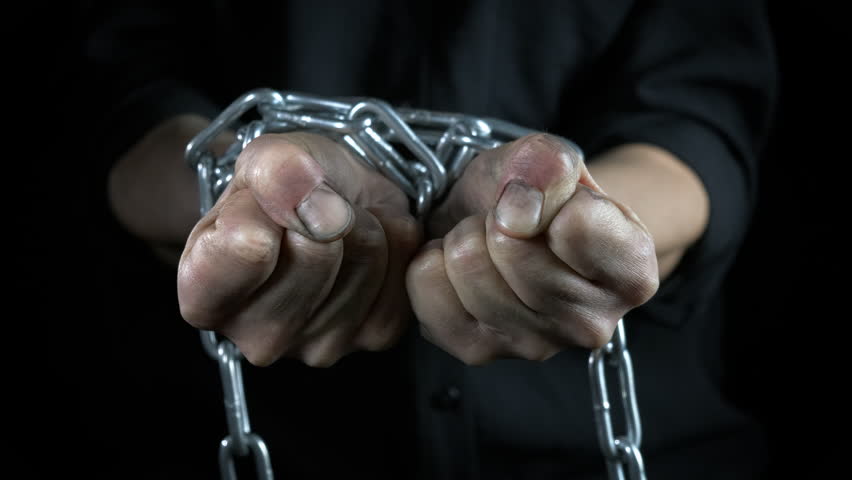 Metal chain on victim hands. A view of metal chain on hands against black background during crisis time.
