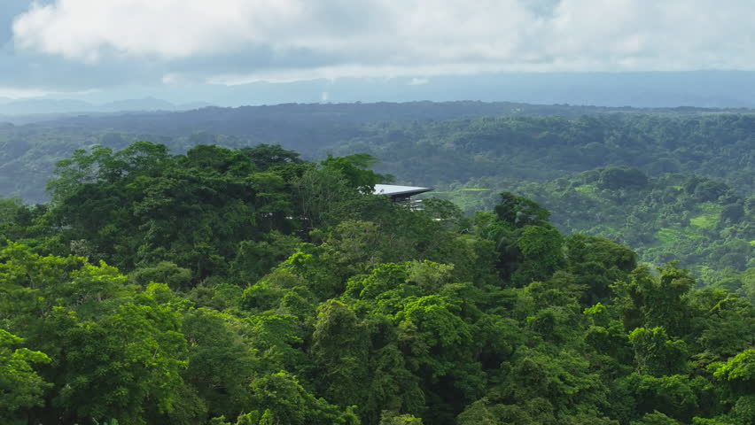 Experience the breathtaking beauty of Costa Rica with an aerial view of a house amid lush forests, showcasing modern architecture that blends with nature, ideal for adventure and serene retreats