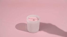 A young woman's hand lights a pink candle with a burning match on a pink isolated background. The concept of creating coziness, decor items, celebration, meditation and relaxation - Powered by Shutterstock - Get 15% off with code: PIKWIZARD15