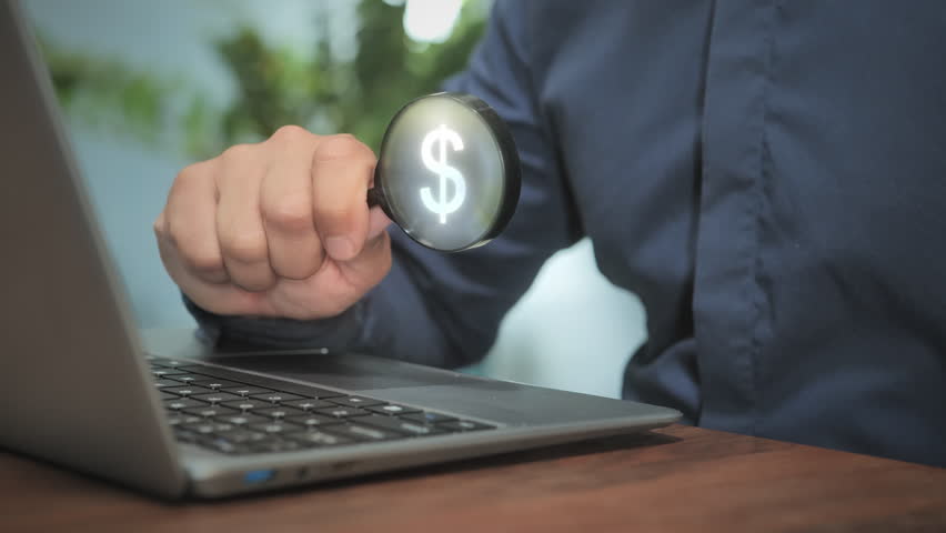 man at laptop computer holding magnifying glass with dollar icon, earning money online concept,investment opportunity