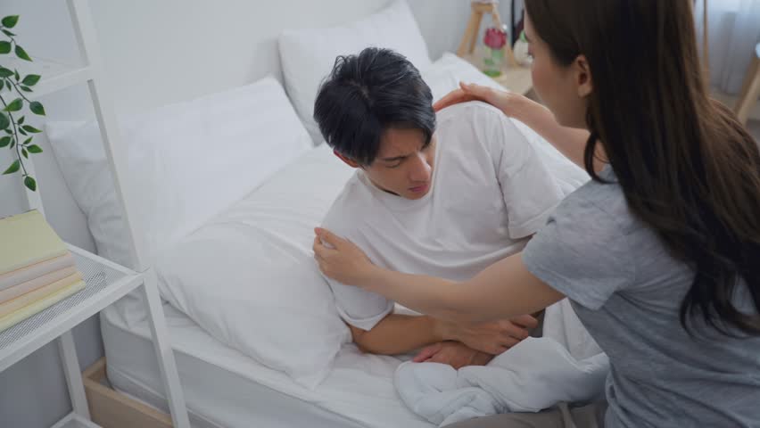 Asian young wife put blanket on sick husband with fever sleeping on bed. Attractive beautiful woman take care and support her sleeping boyfriend lying down in bedroom to rest for health care in house.