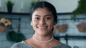 Beautiful Portrait of Happy Mexican Woman Looking at Camera and Smiling on Kitchen Background. Smiley Face of One Young Person Indoors at Home. Native Lifestyle of Optimistic Girl with Dark Hazel Eyes - Powered by Shutterstock - Get 15% off with code: PIKWIZARD15