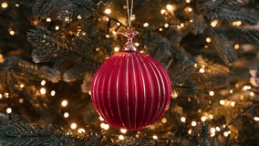 Christmas tree flickering light Christmas red ornament close-up hanging on beautifully lit. Festive bauble is surrounded by glowing string lights pine branches, creating warm cozy holiday atmosphere. - Powered by Shutterstock - Get 15% off with code: PIKWIZARD15