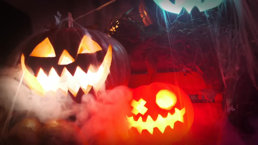 Close up Halloween decorations carved pumpkin lanterns in cobweb stand in mist, party holiday background.