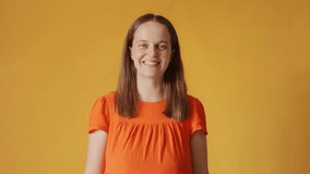 Pleased woman in orange shirt nodding her head with smile listening attentively hearing something important looking content with approval expression and agreement isolated over yellow background - Powered by Shutterstock - Get 15% off with code: PIKWIZARD15