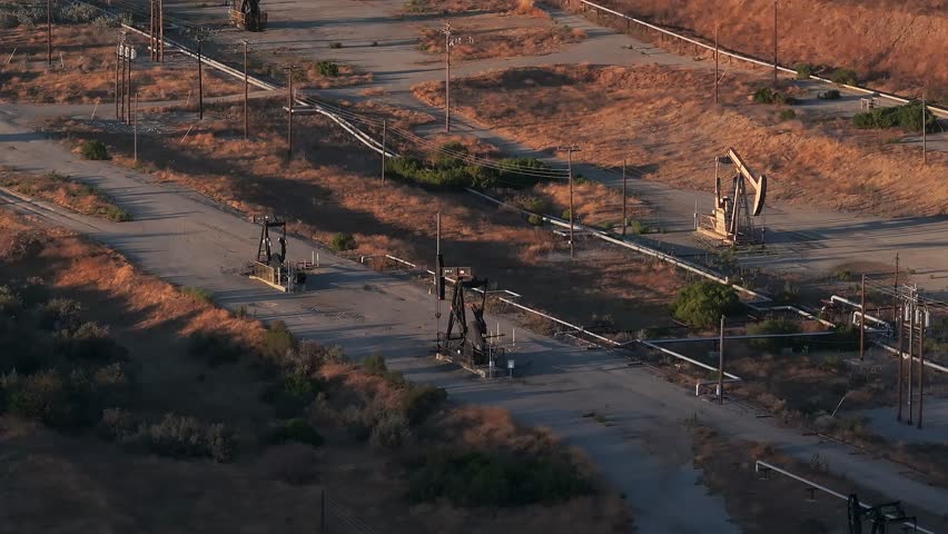 Aerial view of the oil rigs and wells in the Midway-Sunset shale oil fields, the largest in California. A pumpjack operates at an oil field. Oil pump rig energy industrial machine for petroleum.