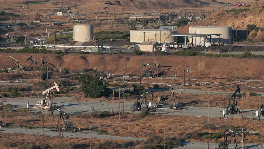 Aerial view of the oil rigs and wells in the Midway-Sunset shale oil fields, the largest in California. A pumpjack operates at an oil field. Oil pump rig energy industrial machine for petroleum.