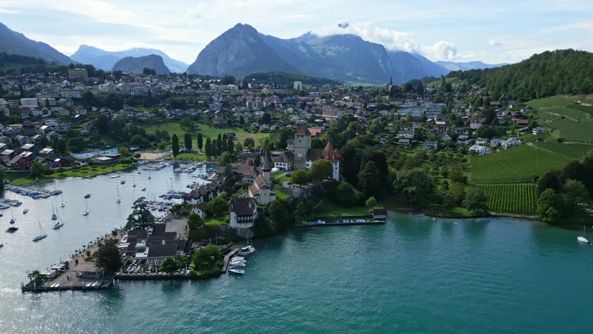 Orbit drone shot of the castle in Spiez with Thun lake in Canton of Bern in Switzerland.