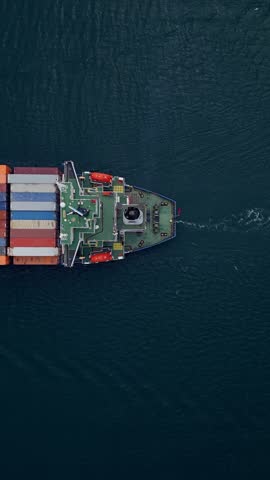 Aerial view of a cargo ship navigating calm waters with colorful shipping containers during daylight