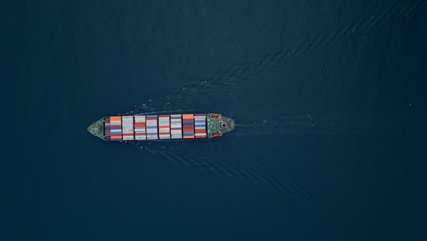 A container ship sails across the calm blue waters
