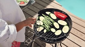 Grilled vegetables on a barbecue grill by the poolside on a sunny day, featuring zucchini, green beans, and a red pepper for a healthy summer meal. - Powered by Shutterstock - Get 15% off with code: PIKWIZARD15