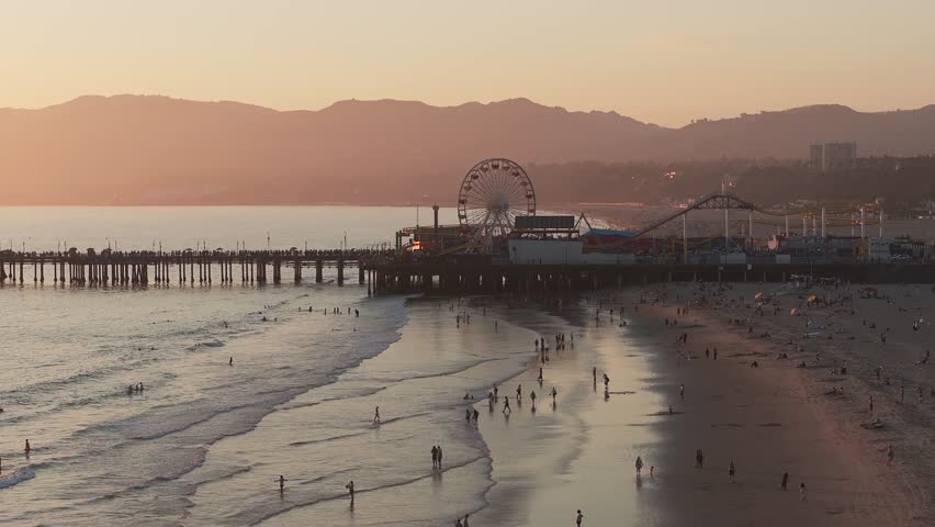 Aerial view of the Santa Monica Pier in California, Los Angeles at sunset. Beautiful summer landscape at the Santa Monica Pier with a Ferris Wheel, rollercoaster, carnival rides and games