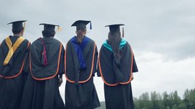 Four graduates are standing in a field, wearing their caps and gowns. Scene is one of celebration and accomplishment, as the graduates have just completed their studies - Powered by Shutterstock - Get 15% off with code: PIKWIZARD15