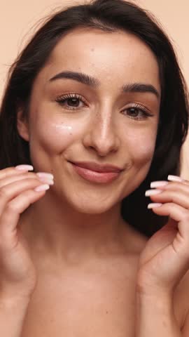 Closeup of a beautiful woman applying moisturizing cream on her face, emphasizing skincare routine and the concept of beauty with a clean, healthy complexion.