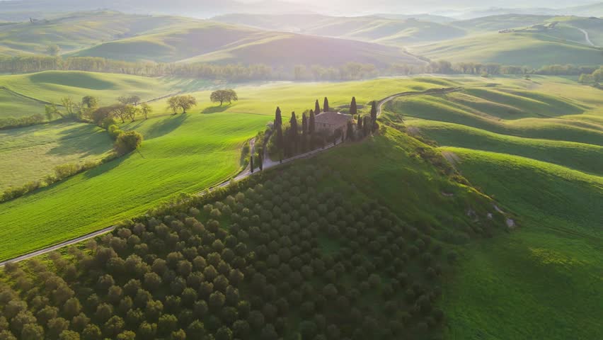 Classic Tuscany landscape with green hills and farmland country at sunrise. Aerial shot of green spring fields and hills in Tuscany, Italy
