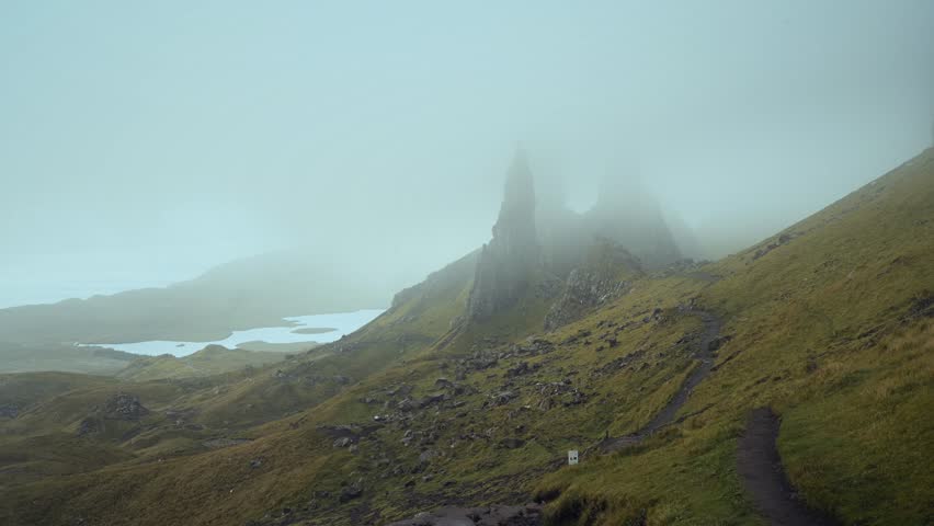 4K Time-Lapse of moving clouds over high sharp cliffs towering over the lakes and sea at sunrise. The Old Man of Storr. The Isle of Skye, Scotland
