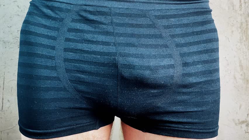 a man in shorts holds a watch with arrows at half past five, the concept of sexual dysfunction. 