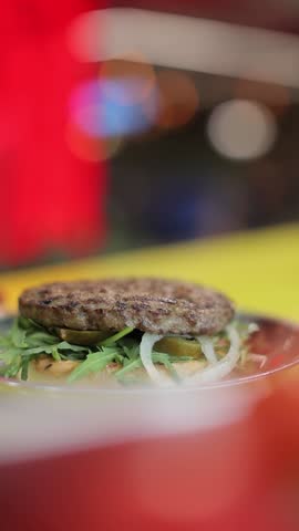 A slow motion closeup vertical footage of a chef making a hamburger, with blurred background
