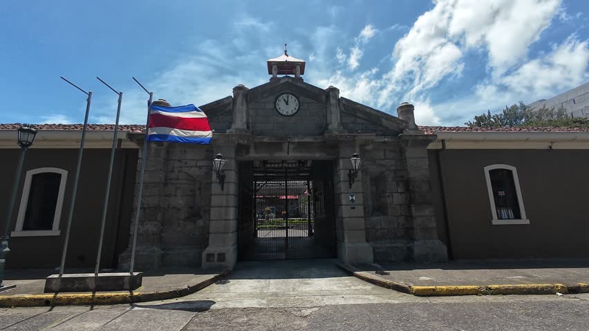 The national flag of Costa Rica waving in front of the National Cultural Center (CENAC) building on a sunny day in San Jose, Costa Rica