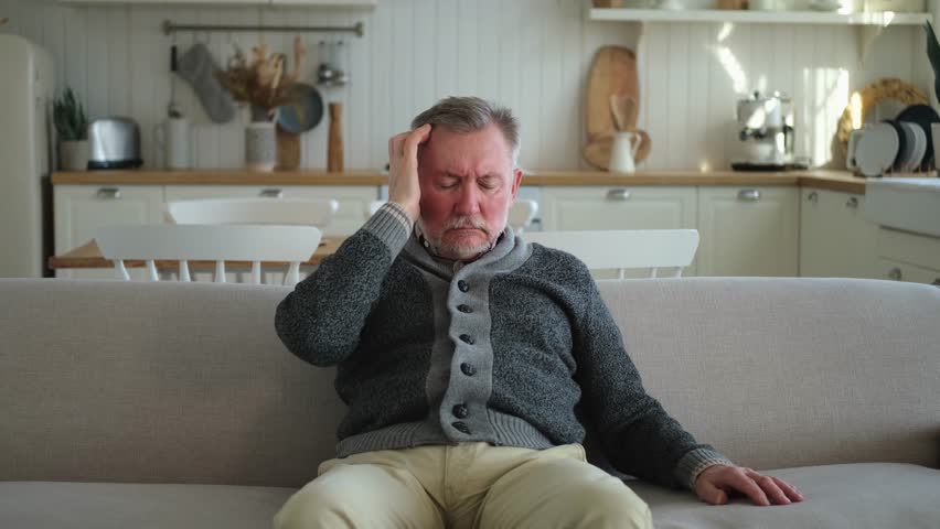 Headache pain. Unhappy middle aged senior man suffering from headache sick rubbing temples at home. Mature old senior grandfather touching temples experiencing stress. Man feeling pain hurt in head