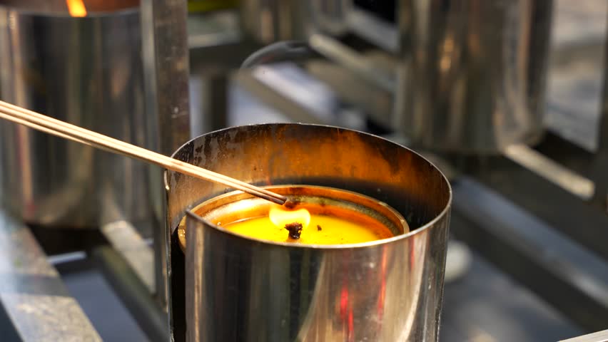 Incense sticks being burned in a candle flame during a prayer ritual at Lama Temple in Beijing