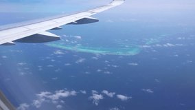 The view from the plane window of the ocean and the atoll. The silver wing of an airplane. There are clouds in places. Turquoise water and snow-white beaches of islands. The Indian Ocean and Maldives - Powered by Shutterstock - Get 15% off with code: PIKWIZARD15