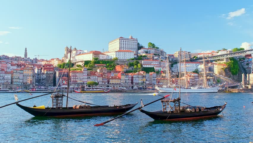 View of Porto city and Douro river with traditional boats with port wine barrels and sailing ship from famous tourist viewpoint Marginal de Gaia riverfront. Porto, Vila Nova de Gaia, Portugal