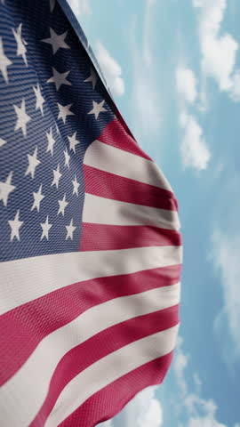 Wavy flag of United States of America blowing in the wind in slow motion. Waving official USA flag team symbol abstract vertical background. Blue sky with clouds. World countries flying flags concept