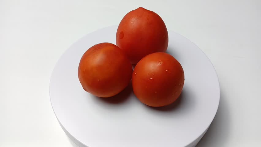 FHD Video of Three Fresh Tomatoes Rotating Slowly on White Background.