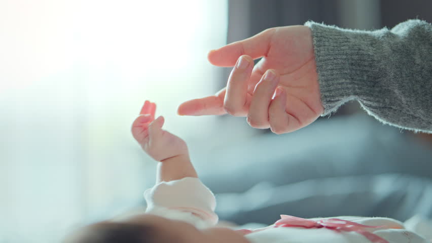 Close-up little hand of child baby holding hand of mother, A newborn holds on to mom's, dad's finger, Love and relationship with infant, Care and support, Dreaming and protection