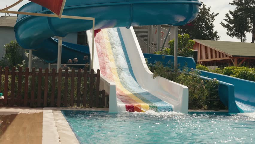 Boy descends from water slide into pool in water park. High quality 4k footage