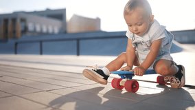 baby rides sitting on a skateboard. happy family kid dream concept. baby son learning to skateboard playing funny video. child lifestyle in a skate park rides a skateboard outdoors - Powered by Shutterstock - Get 15% off with code: PIKWIZARD15