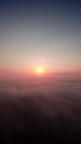 Serene sunrise, a beautiful dawn above morning mist and low moving clouds (Vertical background video)
