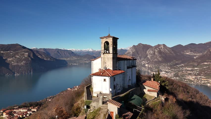 An aerial drone flight around a small chapel in Monte Isola, Italy, on the mountain in winter, capturing the serene beauty of Iseo Lake.