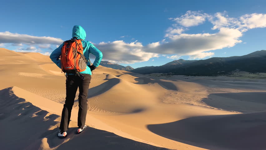 Caucasian successful hiker female at sunrise extreme environment Great Sand Dunes National Park Colorado travel tourism