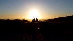 A drone flight captures silhouettes of a couple romantically watching the sunset while sitting on a small mountain top. A beautiful idea for a date. - Powered by Shutterstock - Get 15% off with code: PIKWIZARD15