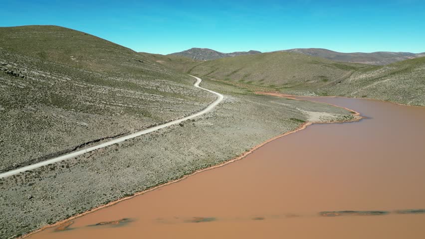 One moto rides remote road past muddy Laguna Llajuapampa in Peru