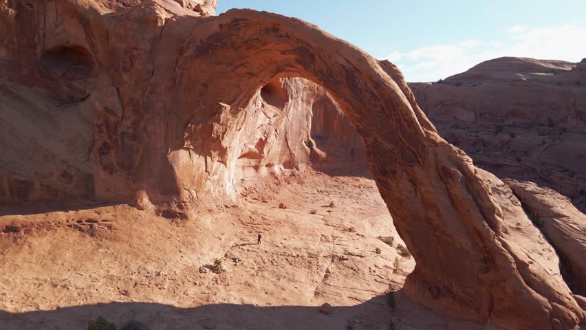 Aerial of a woman hiker walking under the amazing Corona Arch near Moab, Utah, USA.