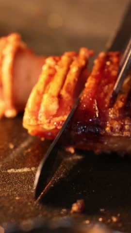 the process of slicing meat using kitchen knives and utensils in soft light restaurant kitchen