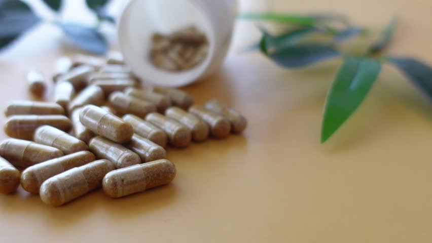 closeup of herbal medicine capsules and container on table 